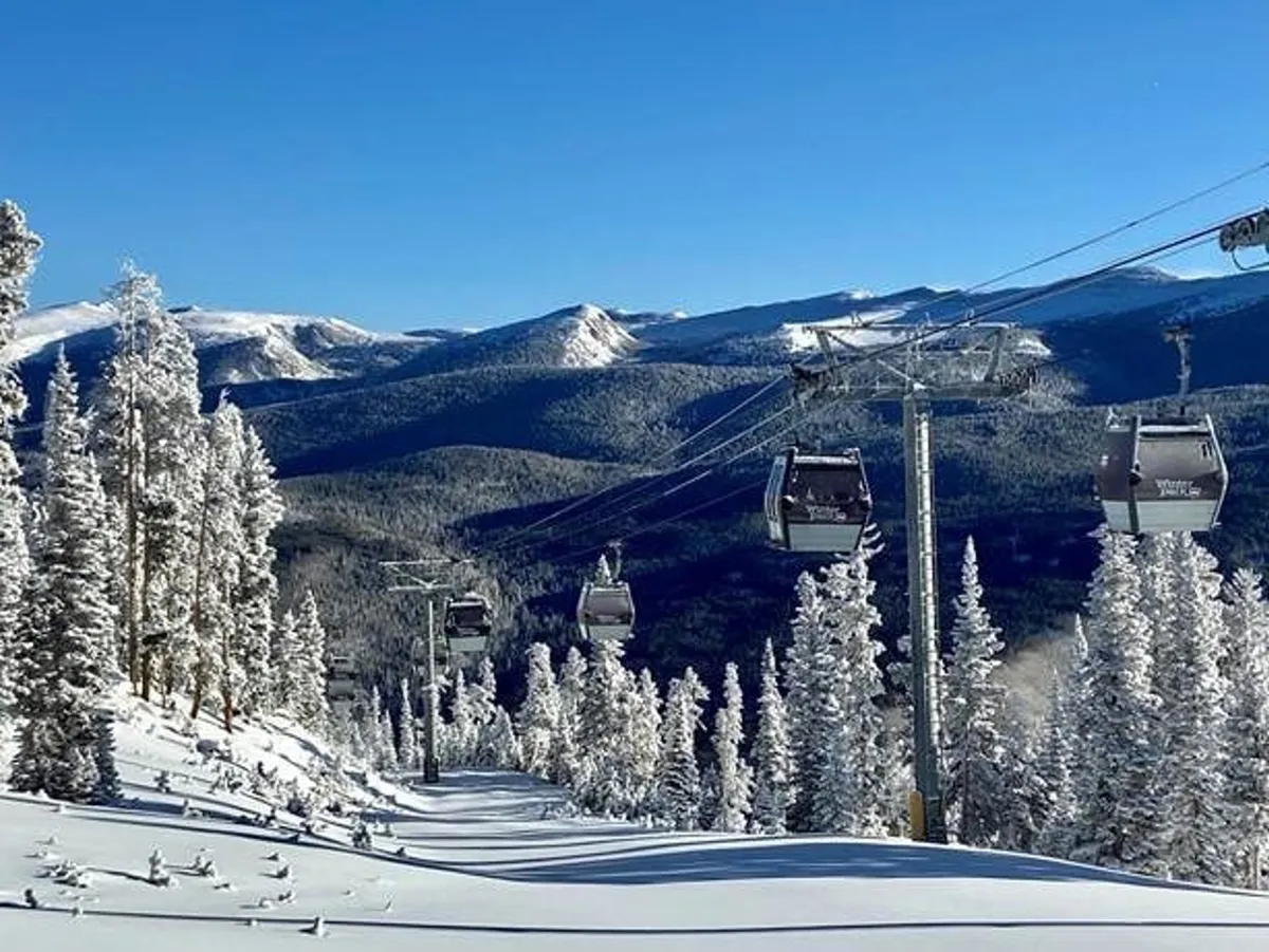 A snow-dusted mountain landscape with a ski lift rising among the trees, inviting guests to explore thrilling winter sports. The sky is clear, and the setting is alive with anticipation for skiing and snowboarding at Winter Park Resort.
