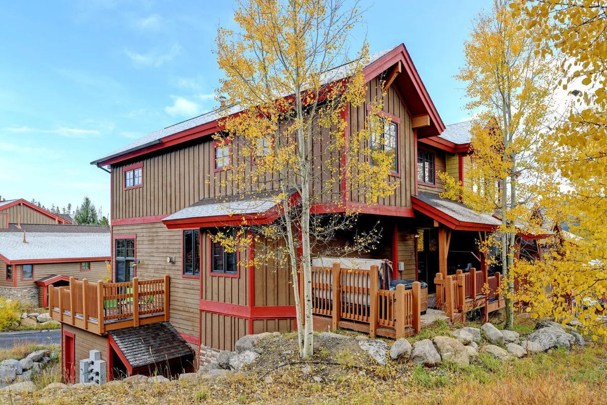 A spacious wooden deck overlooks colorful foliage, with architectural details of the villa visible and ample space for gatherings or peaceful relaxation outdoors. The welcoming mood hints at both privacy and the opportunity to enjoy scenic views from the home.